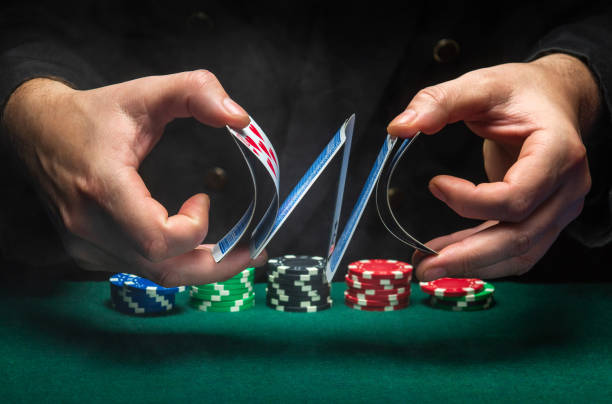 An experienced dealer or croupier shuffles playing cards in a club over a green table with playing chips. The concept of playing poker in a casino or club An experienced dealer or croupier shuffles playing cards in a club over a green table with playing chips. The concept of playing poker in a casino or club. dibs stock pictures, royalty-free photos & images