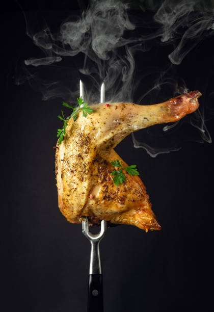 istock Oven baked chicken thigh with parsley on a fork. Menu or recipe concept for restaurant or hotel on black background 1484314327
