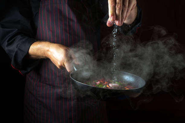 istock Experienced chef adds salt to a steaming hot pan. Molecular cuisine menu idea for a hotel with advertising space 1484314333