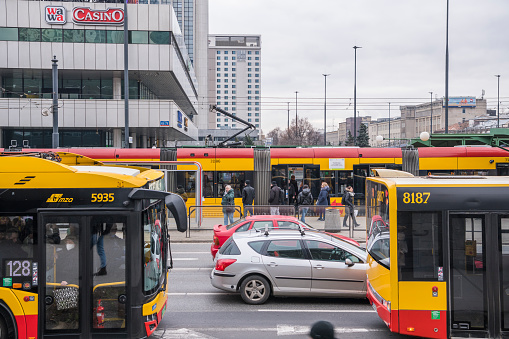 Public transport, streetcar and busses  in the streets of Warsaw during morning rush hour with cars in between and passengers. 5 april 2023, Warsaw, Poland