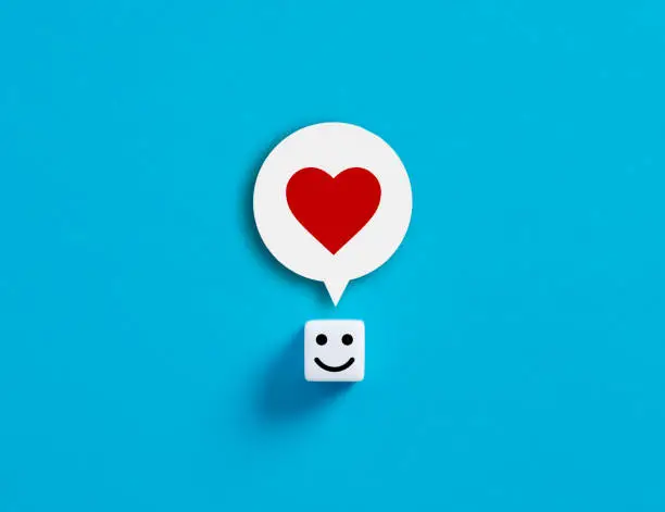 Photo of Love, happiness or social media like concepts. Cube with happy face with a heart symbol in its head.