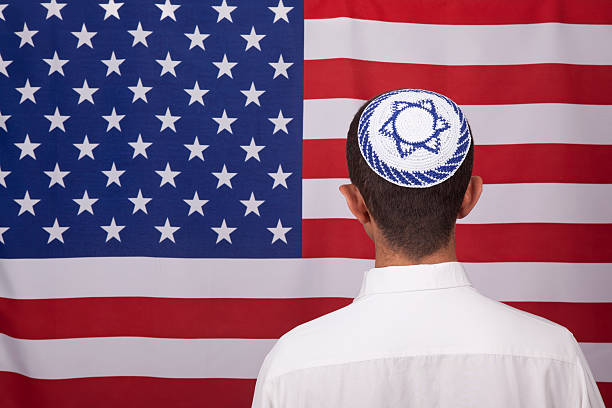 Jewish Citizen Wearing Yarmulke In Front Of American Flag back View Of Jewish Citizen Wearing Yarmulke In Front Of American Flag for multi-ethnicity nature of USA yarmulke photos stock pictures, royalty-free photos & images