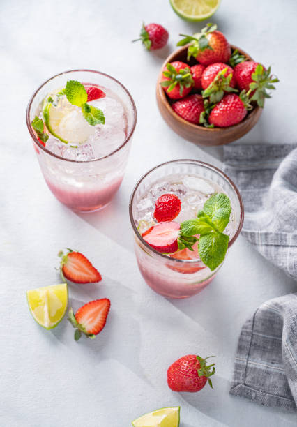 istock Fresh strawberry mojito in a glass with berries, lime, mint and ice on a light background with shadow. The concept of a summer refreshing drink for a party 1484321427