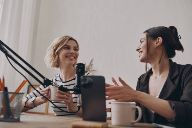istock Two beautiful young women talking and smiling while podcasting in recording studio 1484323241