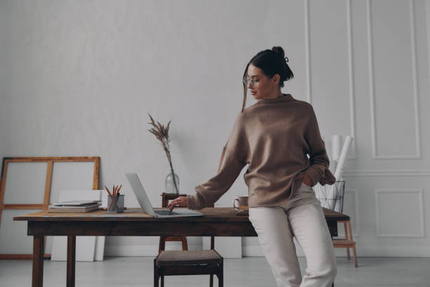 istock Beautiful young woman using laptop while leaning at the desk in creative office 1484325409