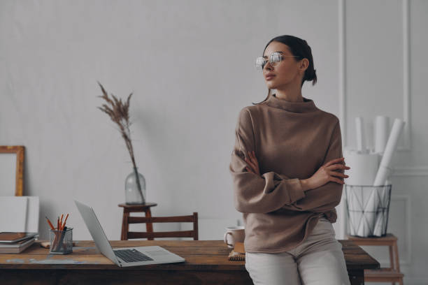 istock Beautiful young woman looking thoughtful while leaning at the desk in creative office 1484325428