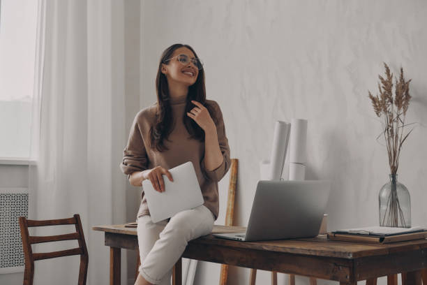 istock Happy young woman holding digital tablet while sitting on the desk in creative office 1484325527