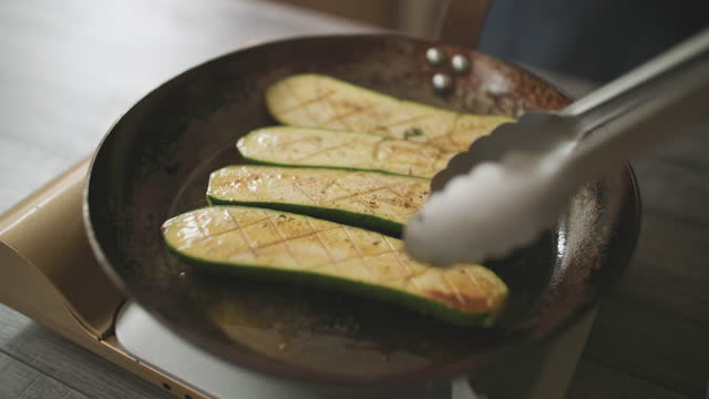frying half courgette in an iron pan