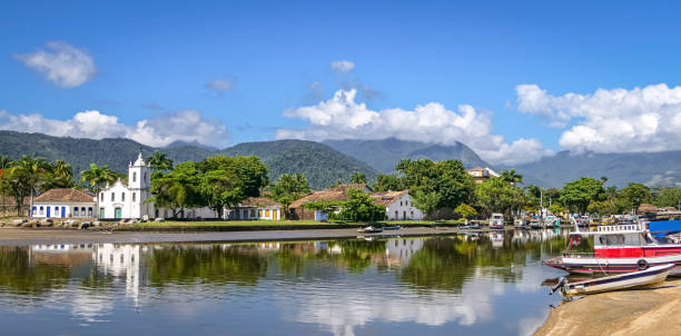 istock Panoramic view to Igreja Nossa Senhora das Dores (Church of Our Lady of Sorrows) with water reflections in the tidal river and mountains in background, historic town Paraty, Brazil 1484330238