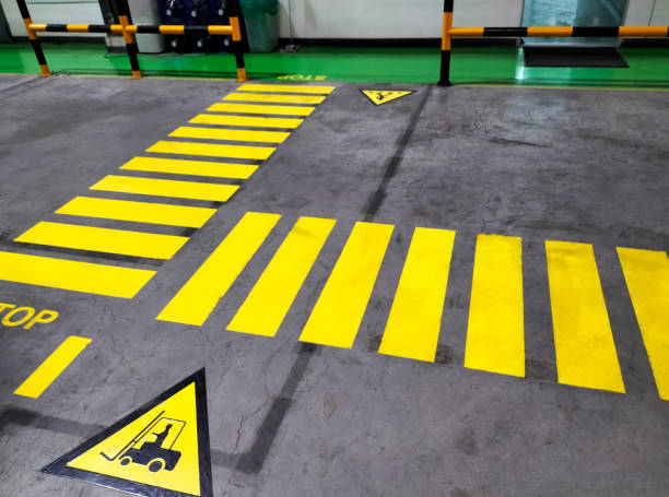 walkway Walkway signs and painted yellow on the factory floor. Signs for safe passage at industrial plants central reservation stock pictures, royalty-free photos & images