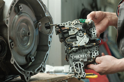 An auto mechanic performs work on replacing the torque converter in the CVT variator, oil purification filters, valve control unit.