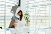 Frustrated businesswoman throwing her computer in the office.