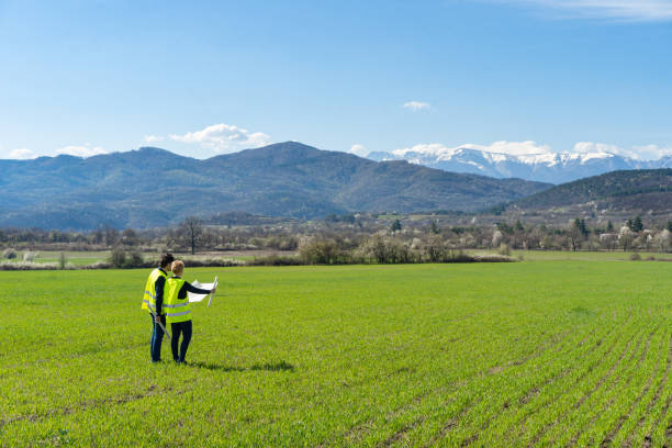 dwóch inżynierów zrównoważonej energii stojących w polu i przyglądających się planom - mountain mountain peak snow spring zdjęcia i obrazy z banku zdjęć