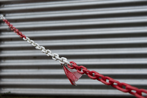 diagonal red and white chain in front of a corrugated iron wall