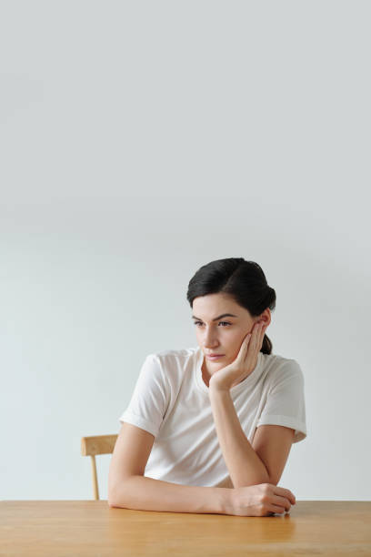 istock Pensive Woman Sitting at Table 1484354437
