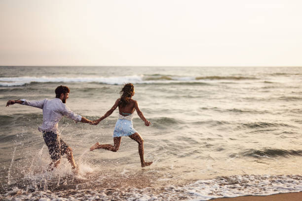istock Cheerful couple running through sea on the beach. 1484361208