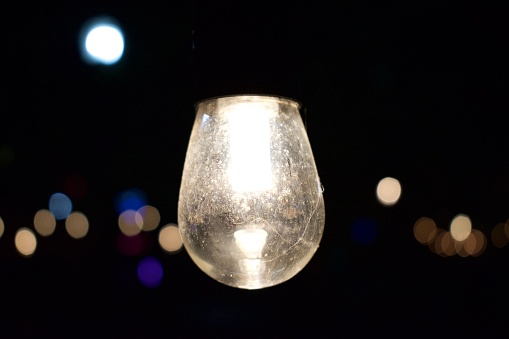 A closeup of a glowing light bulb suspended in darkness