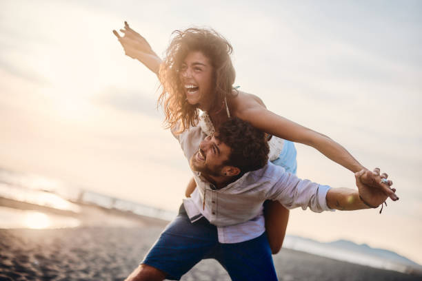 istock Young playful couple having fun while piggybacking on the beach. 1484368551