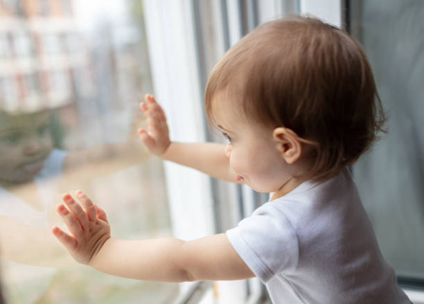 istock One year old child looking trough the window 1484369079