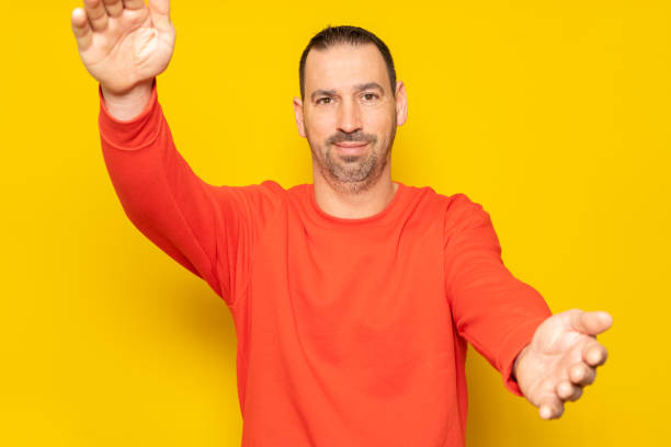 istock You did it. Congratulations. Happy cheerful positive hispanic man with beard standing over yellow colored background looking at camera, smiling and opening arms for warm hug. 1484374766