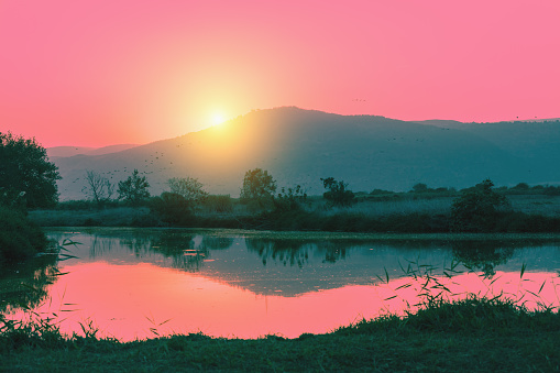Mountain landscape in the evening. Beautiful lake against mountains. The Hula Valley in northern Israel at sunset