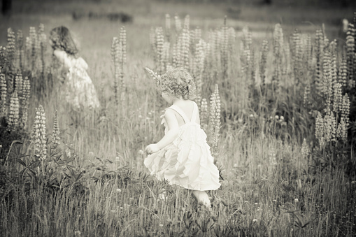Two beautiful girls running in a large open field.  Very shallow depth of field. Note: there is some motion blur from running.