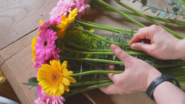 Flower arrangement of gerbera transvaal daisies close up from the florist over shoulder view in slow motion 4K