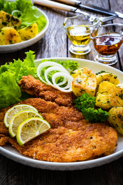istock Breaded fried pork chop with fried potatoes and lime on wooden table 1484385989