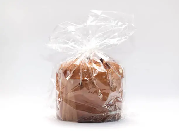 Isolated Panettone Italian Christmas Cake In Cellophane, Package On White Background. Fruitcake, Sweet bread, Originally From Milan, Italy. Pastry Dessert. Horizontal plane. High quality photo