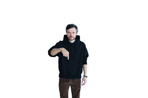 Young bearded serious handsome man in casual clothes posing isolated on white background and pointing finger down