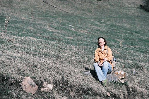 Female mountain hiker is sitting on the rock