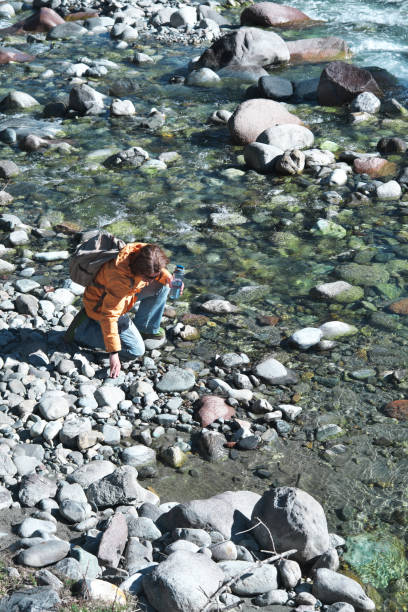 istock Female mountain hiker is washing hands and face in mountain river 1484423780