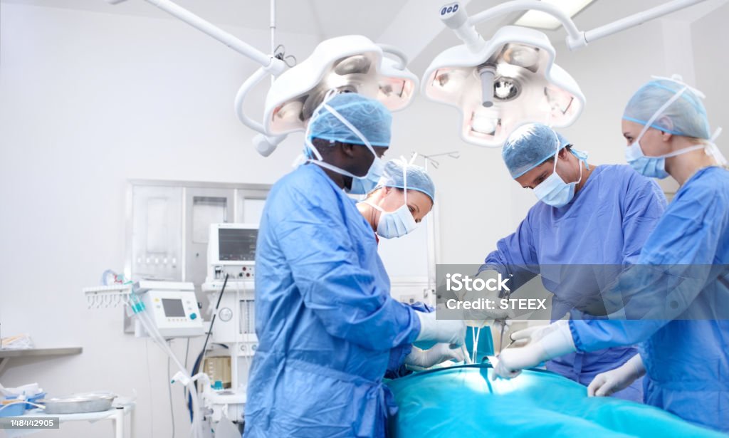 Let your copyspace tell families the good news Medical surgeons performing surgery in an operating theatre together - Copyspace Operating Room Stock Photo