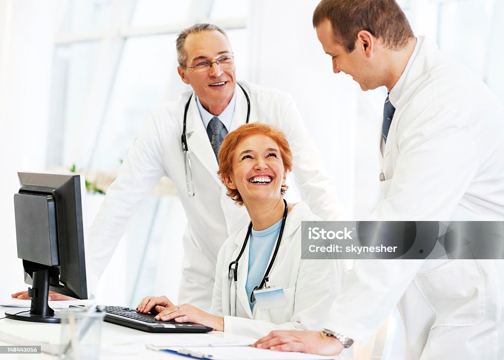Grupo de médicos trabajando en una computadora - Foto de stock de Reírse libre de derechos