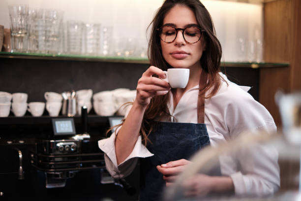 Ritratto di una cameriera in piedi al bar e provare il caffè. - foto stock