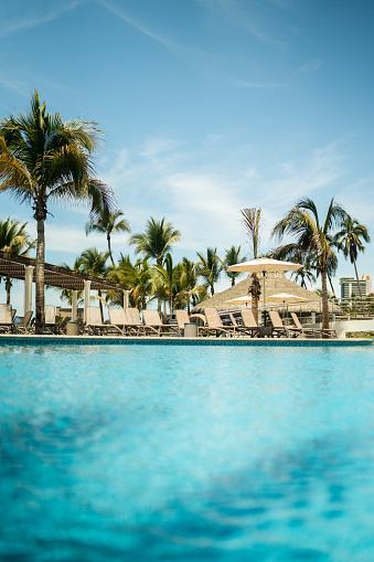 Young caucasian woman in swimming pool on beautiful tropical bay, blue sky and ocean, summer vacation concept.