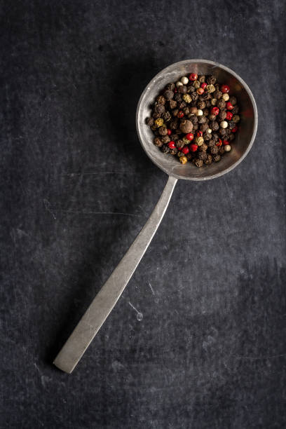 istock Big old spoon with peppercorn on black background 1484447492