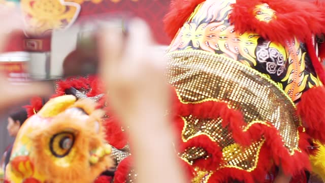 Man's hand using a smartphone to record a lion dance during Chinese New Year.