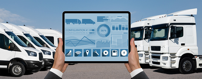 Manager with a digital tablet on the background of vans and trucks. Fleet management