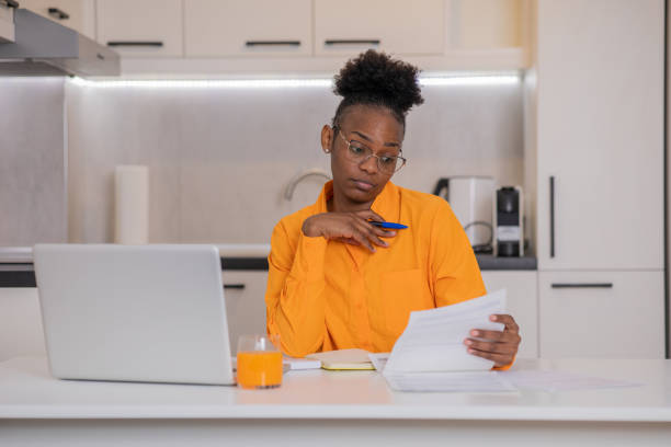 istock Young woman using calculator while going through bills and home finances 1484466287