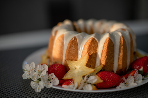 Delicious kugelhopf cake decorated with white chocolate, strawberry fruit, star fruit / carambola fruit and white flowers on the table