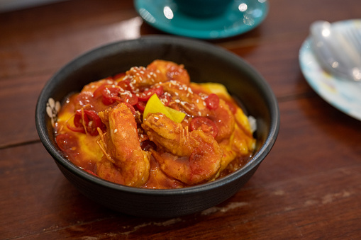 Fried sticky shrimps with garlic, chilli, and pineapple served with rice close-up in a bowl.