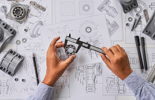 Engineer technician designing drawings mechanicalÂ parts engineering Engine
manufacturing factory Industry Industrial work project blueprints measuring bearings caliper tools