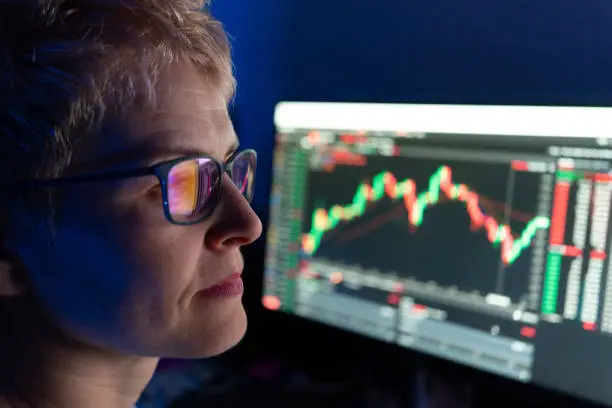 Photo of Woman illuminated by line graph on digital screen