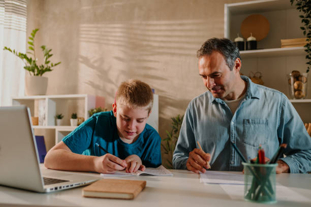 istock Proud father watching his son doing his homework while both enjoying at home. 1484473053