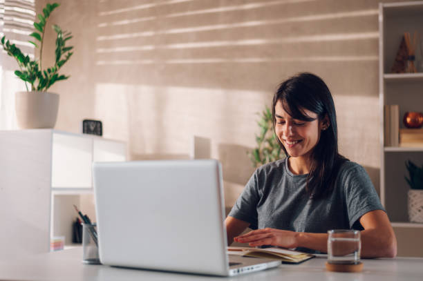 istock Satisfied young boss lady smiling and sitting at her desk while typing new ideas 1484473095