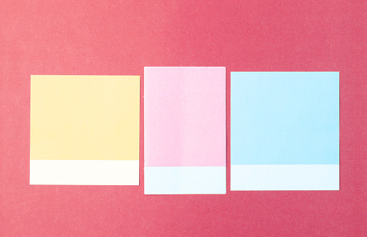 3 blank multi-colored post it notes on red background.