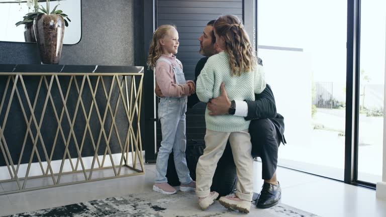 Hug, speaking and a father with children after work, arriving home and kids happy to see dad. Love, affection and a man hugging daughters after coming from job, talking and embracing at the door