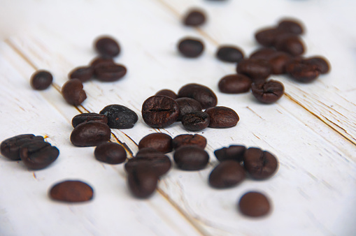 Scattered coffee beans on wooden cover background with customizable space for text or coffee ideas.