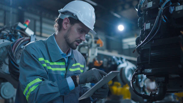istock Professional industrial engineer, technician, factory worker wear hard hat safety. While set up, control machine heavy industry factory. Employee working in manufacturing facility 1484484223